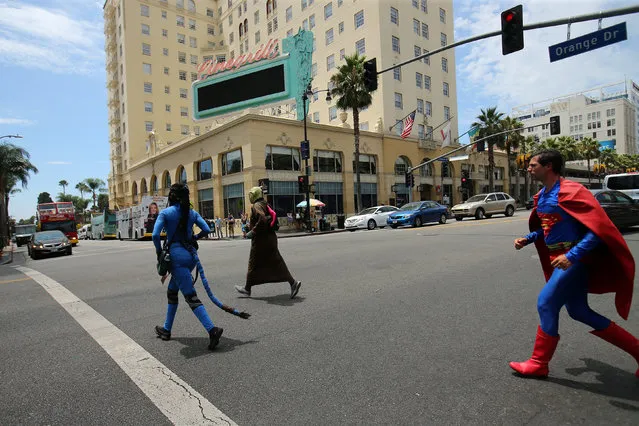 People dressed as characters from movies look run across Hollywood Boulevard  towards a group of tourists arriving in Hollywood, California, U.S. August 3, 2017. (Photo by Mike Blake/Reuters)