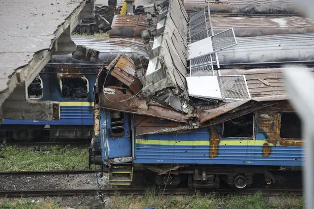 A collapsed bridge lies on burned-out wagons standing on the tracks at the station in Mariupol, in an area controlled by Russian-backed separatist forces, eastern Ukraine, Monday, July 11, 2022. (Photo by AP Photo/Stringer)