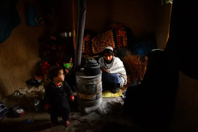 In this photo taken on January 14, 2020, an Internally-displaced family warm themselves around a wood-burning stove at a refugee camp on the outskirts of Herat. Avalanches, flooding and harsh winter weather killed more than 130 people across Pakistan and Afghanistan in recent days, leaving others stranded by heavy snowfall, officials said on January 14. (Photo by Hoshang Hashimi/AFP Photo)