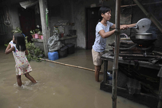 Residents cook outside their house in a flooded village after Typhoon Yinxing, locally called Marce, blew past Buguey town, Cagayan province, northern Philippines on Friday November 8, 2024. (Photo by Noel Celis/AP Photo)