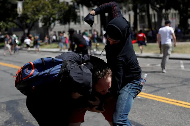 A photographer is being attacked by masked demonstrators in Martin Luther King Jr. Civic Center Park during a cancelled No Marxism in America rally and counter-protest in Berkeley, California, U.S. August 27, 2017. (Photo by Stephen Lam/Reuters)