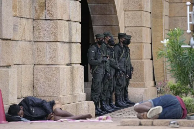 Army soldiers stand guard as protesters sleep by the entrance to president's office in Colombo, Sri Lanka, Friday, July 15, 2022. (Photo by Eranga Jayawardena/AP Photo)