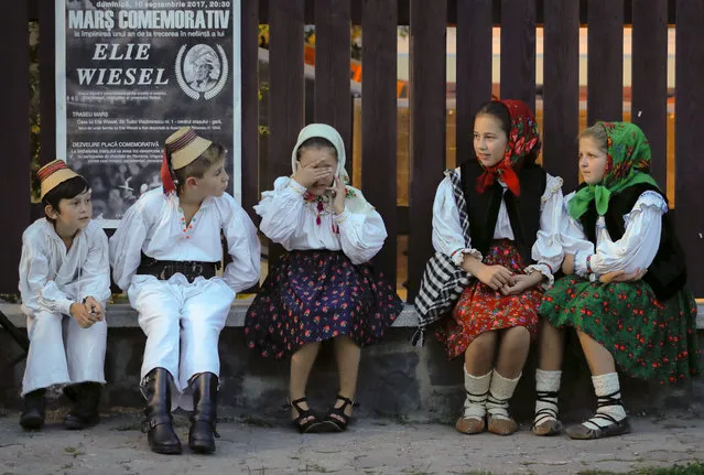 Children wearing traditional outfits wait before a march marking one year since the death of Nobel laureate and Holocaust survivor Elie Wiesel in Sighetu Marmatiei, northern Romania, Sunday, September 10, 2017. Hundreds marched on Sunday in Wiesel's Romanian hometown, the scene of mass deportation of Jews to Nazi death camps in 1944. (Photo by Vadim Ghirda/AP Photo)