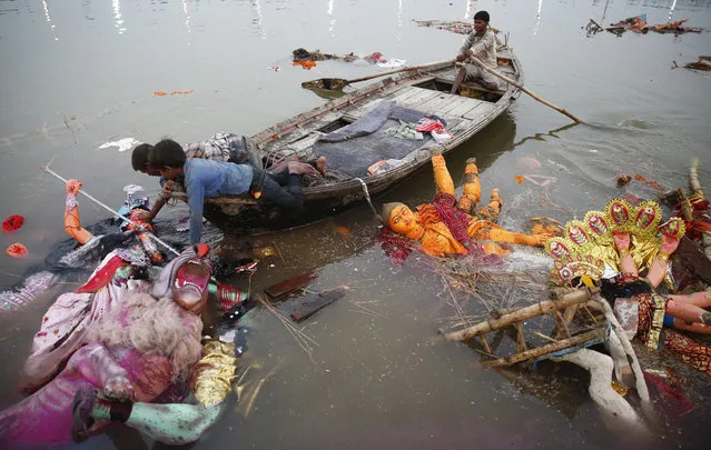 Indian boys pull an idol of Hindu goddess Durga to shore to clean up the temporary water body beside the Ganges river, after immersion of Durga idols by Hindu devotees in Allahabad, India, Saturday, September 30, 2017. (Photo by Rajesh Kumar Singh/AP Photo)