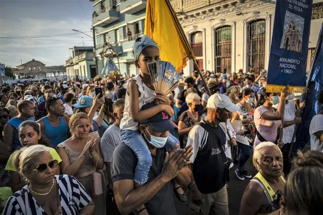 Faithful accompany a statue of the Virgin of Regla during a procession honoring the black Madonna, in the town of Regla, across the bay from Havana, Cuba, Wednesday, September 7, 2022. The black Madonna is honored on the same day as Cuba's patron saint, the Virgin of Charity, both of which are also recognized as powerful deities in the African-influenced religion of Santeria. (Photo by Ramon Espinosa/AP Photo)