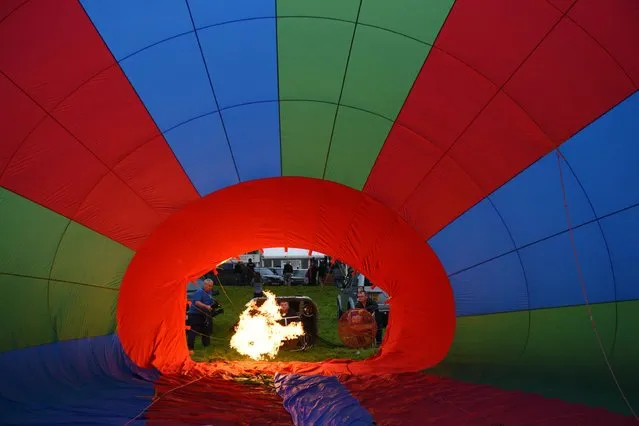 Balloonists inflate their hot air balloons on the second day of the Bristol International Balloon Fiesta in Bristol, southwest England, on August 12, 2016. The Fiesta features over 150 hot air balloons from around the world. The event runs from August 11th to the 14th on the Ashton Court Estate in Bristol. (Photo by Oli Scarff/AFP Photo)