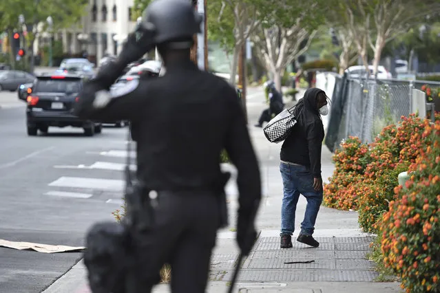 A looter walks away from a police officer in downtown Walnut Creek, Calif., on Sunday, May 31, 2020. (Photo by Jose Carlos Fajardo/Bay Area News Group)