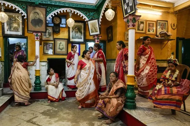 Women in traditional attire wait with a Kumari, right, a virgin girl worshipped as an incarnation of Goddess Durga, at a residence during Durga Puja festival, in Kolkata, India, Tuesday, October 4, 2022. The five-day festival commemorates the slaying of a demon king by lion-riding, 10-armed goddess Durga, marking the triumph of good over evil. (Photo by Bikas Das/AP Photo)