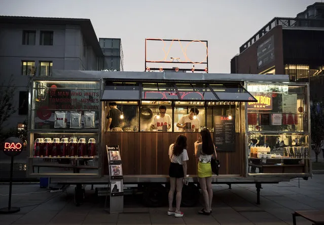 Chinese buy drinks outside a bar in the trendy Sanlitun neighborhood on September 5, 2014 in Beijing, China. The shopping district, known for its high end shops and restaurants is frequented by affluent locals and foreigners. (Photo by Kevin Frayer/Getty Images)