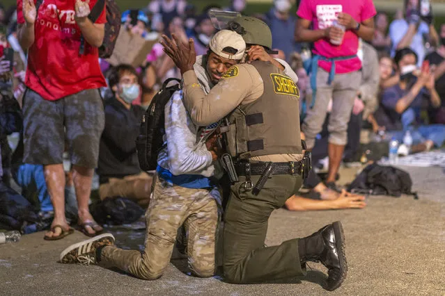 An African American protester and an African American Los Angeles County Sheriff's Department deputy embrace in solidarity as officers prepare to arrest a large group of people demonstrating past curfew over the death of George Floyd on June 3, 2020 in Los Angeles, California. The vast majority of protesters demonstrated peacefully. Former Minneapolis police officer Derek Chauvin was taken into custody for Floyd's death. Chauvin has been accused of kneeling on Floyd's neck as he pleaded with him about not being able to breathe. Floyd was pronounced dead a short while later. Chauvin and 3 other officers, who were involved in the arrest, were fired from the police department and charged with murder after a video of the arrest was circulated. (Photo by David McNew/Getty Images)