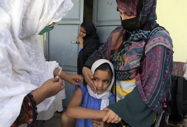 A schoolgirl receives a typhoid fever vaccine during a vaccination campaign in Peshawar, Pakistan, Monday, October 3, 2022. According to the health department, all children between the age of 9 months and 15 years will be vaccinated in the first phase of the campaign. (Photo by Muhammad Sajjad/AP Photo)