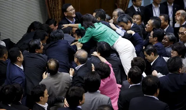Opposition Democratic Party of Japan lawmaker Hiroe Makiyama (green) climbs over other lawmakers who are guarding Yoshitada Konoike, chairman of the upper house special committee on security, before a vote at an upper house special committee session on security-related legislation at the parliament in Tokyo, Japan, September 17, 2015. (Photo by Toru Hanai/Reuters)