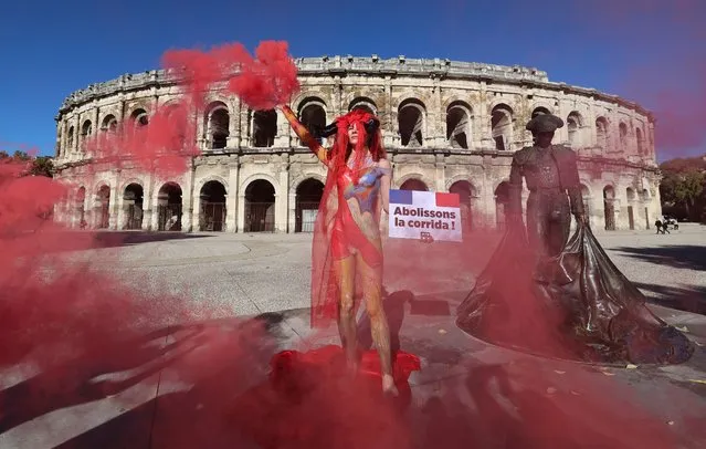 French actress Marie Cornillon wearing body paint and a headgear with bull horns, poses in front of the Nimes arena with a sign inscribed “Abolissons la corrida” (Abolish corrida bullfighting) as part of a protest by the People for the Ethical Treatment of Animals (PETA) animal rights group to ban bullfighting in France, on November 16, 2022. (Photo by Pascal Guyot/AFP Photo)