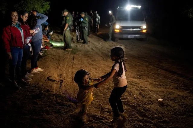 Two year old migrant, Reina of Nicaragua, plays with five year old compatriot, Ashley, as border patrol agents process asylum seeking migrants who were smuggled from Mexico into Roma, Texas, U.S., November 6, 2022. (Photo by Adrees Latif/Reuters)