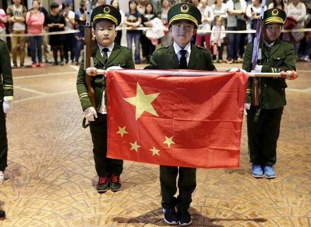 Children wearing uniforms hold a folded Chinese National flag during a military parade game on China's National Day, at Beyou World, a centre where children can experience different kinds of professions, in Beijing, October 1, 2015. (Photo by Reuters/Stringer)
