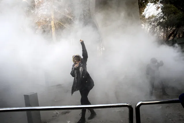 In this photo taken by an individual not employed by the Associated Press and obtained by the AP outside Iran, a university student attends a protest inside Tehran University while a smoke grenade is thrown by anti-riot Iranian police, in Tehran, Iran, Saturday, December 30, 2017. A wave of spontaneous protests over Iran's weak economy swept into Tehran on Saturday, with college students and others chanting against the government just hours after hard-liners held their own rally in support of the Islamic Republic's clerical establishment. (Photo by AP Photo/Stringer)