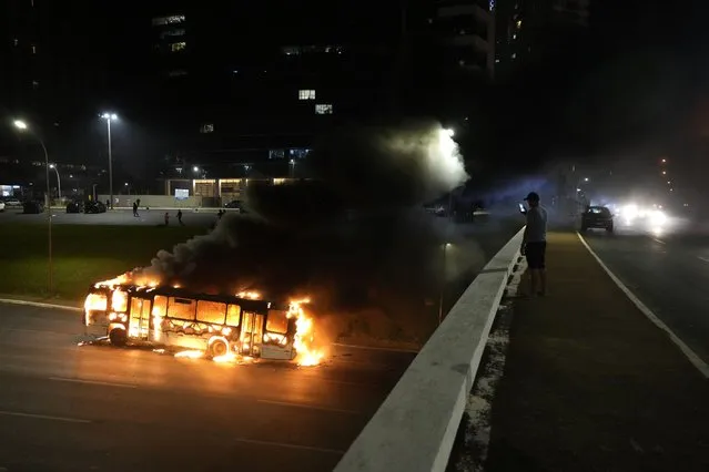 Supporters of Brazilian President Jair Bolsonaro clash with police setting fire to several vehicles and allegedly trying to storm the headquarters of the Federal Police in Brasilia, Brazil, Monday, December 12, 2022. Since Bolsonaro lost re-election to Luiz Inácio Lula da Silva on Oct. 30, his supporters have gathered across the country refusing to concede defeat and asking for the armed forces to intervene. (Photo by Eraldo Peres/AP Photo)