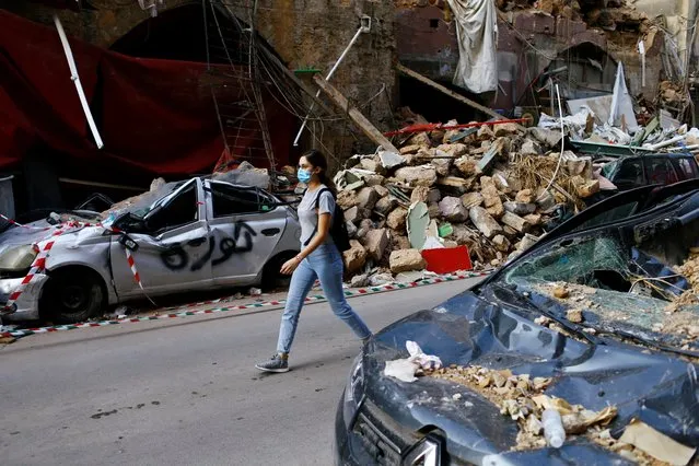 A woman walks past a damaged area in Beirut, August 11, 2020. A walk through Beirut's central neighborhoods revealed mangled buildings and heaps of debris sometimes piled so high that they blocked the narrow streets, hampering cleanup operations. (Photo by Thaier Al-Sudani/Reuters)