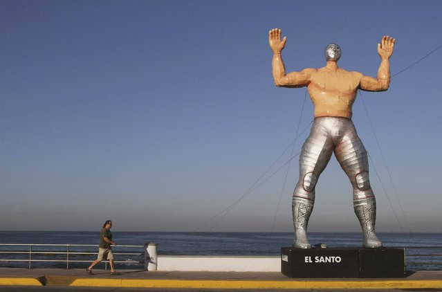 A person walks past a giant figure of famous Lucha Libre wrestler El Santo in Mazatlan January 24, 2013. The municipality set up eight giant figures made by Mexican artist Jorge Gonzalez Neri for the upcoming carnival celebrations. (Photo by Stringer/Reuters)