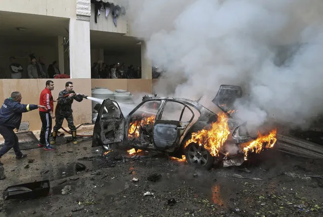 Firefighters extinguish a burning car that was destroyed in a bombing, in the southern port city of Sidon, Lebanon, Sunday, January 14, 2018. The Lebanese military said the bomb went off in a car in southern Lebanon, wounding its Palestinian owner. It was not immediately clear who carried out Sunday's bombing in the city of Sidon or why the Palestinian, identified as Mohammed Hamdan, was targeted. (Photo by Mohammed Zaatari/AP Photo)