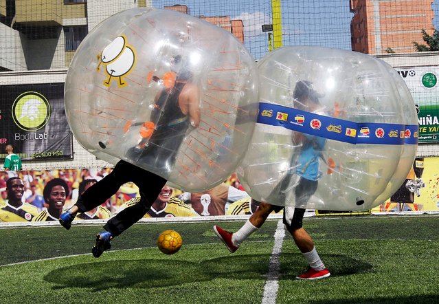 People take part in a game of 'bubble bump soccer' during an exhibition tournament in Medellin, Colombia, October 10, 2015. The game is played by five-a-side teams wearing inflatable balls trying to score goals against the opposing team. (Photo by Fredy Builes/Reuters)