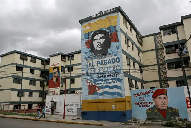 People walk past murals of Venezuela's late president Hugo Chavez and Argentine revolutionary hero Ernesto “Che” Guevara (C) in Caracas, Venezuela September 8, 2016. (Photo by Henry Romero/Reuters)