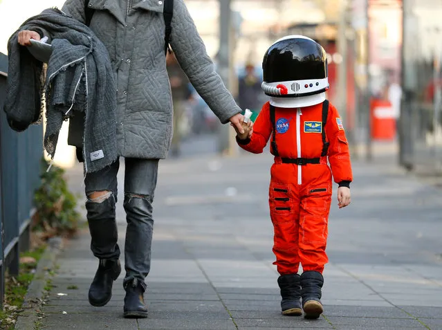 A carnival reveller walks with a kid during “Weiberfastnacht” (Women's Carnival) in Cologne, Germany February 8, 2018, marking the start of a week of street festivals with the highlight “Rosenmontag”, Rose Monday processions. (Photo by Thilo Schmuelgen/Reuters)