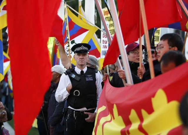 A police officer stands between supporters of China's President Xi Jinping waving Chinese flags and Pro-Tibet supporters waving their flags opposite Big Ben in Parliament Square ahead of Xi's address to both Houses of Parliament, in London, Britain, October 20, 2015. (Photo by Peter Nicholls/Reuters)