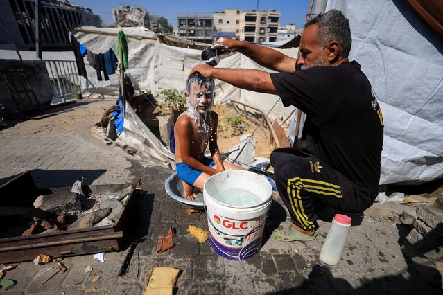 A Palestinian man, displaced by the Israeli offensive, bathes his son inside their shelter amid summer heat, in Gaza City, on July 3, 2025. (Photo by Dawoud Abu Alkas/Reuters)