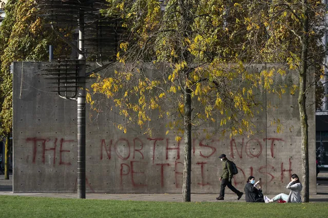 A man walks past graffiti referring to coronavirus, in Manchester city centre, England, Tuesday October 20, 2020. The UK government has adopted a three-tier system for England, with areas classed as medium, high of very high risk. So far, only the Liverpool and Lancashire regions of northwest England have been placed in the highest tier. Nearby Greater Manchester, with a population of almost 3 million, has been holding out for more support for workers and businesses affected by the restrictions. (Photo by Jon Super/AP Photo)