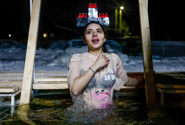 A woman takes a dip in icy water during celebrations of the Orthodox Christian feast of Epiphany in Pereslavl-Zalessky, Yaroslavl region, Russia on January 18, 2022. (Photo by Maxim Shemetov/Reuters)