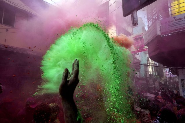 A devotee throws colored powder to others during celebration of the Holi festival on the onset of spring in Kolkata, India, Sunday, March 5, 2023. Millions of Indians on Wednesday celebrated the “Holi” festival, dancing to the beat of drums and smearing each other with green, yellow and red colors and exchanging sweets in homes, parks and streets. Free from mask and other COVID-19 restrictions after two years, they also drenched each other with colored water. (Photo by Bikas Das/AP Photo)