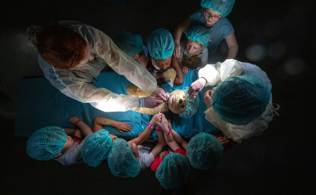 Medical students from the University of Halle operate on a teddy bear together with children from the “Weingärten” daycare center in a real operating theatre in the former emergency room at the University Hospital Halle/Saale in Saxony-Anhalt, Halle on May 14, 2024. This is the 20th time that cuddly toys have been operated on at the University Hospital. The Teddy Bear Hospital in Halle stands out because it uses an entire former hospital wing with several real operating theaters on the Steintor Medical Campus. The aim of the project is to playfully take away children's fear of visiting a doctor. Once again, hundreds of children are expected. The Teddy Clinic runs until Friday. (Photo by Hendrik Schmidt/dpa via Getty Images)