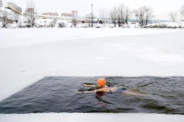A woman from a local cold water training and winter swimming community bathes in an ice hole on Lake Blyudtse (Saucer) in Novosibirsk, Russia on November 21, 2020. (Photo by Kirill Kukhmar/TASS)