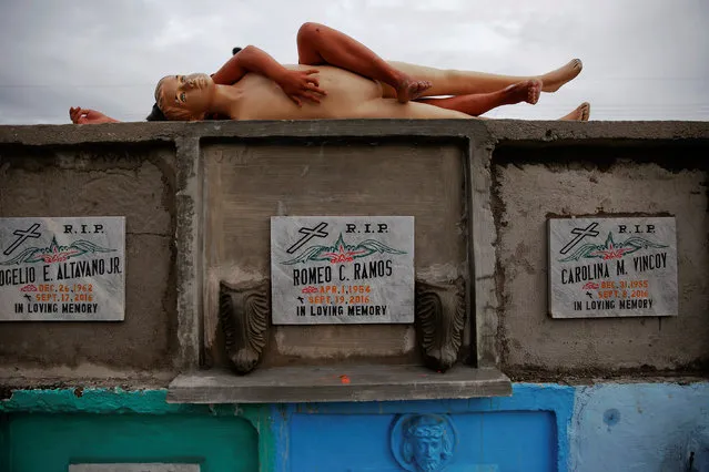 A child plays with a mannequin on freshly constructed apartment-style tombs where some of victims of country's war on drugs are buried at he North Cemetery in Manila, Philippines October 16, 2016. (Photo by Damir Sagolj/Reuters)