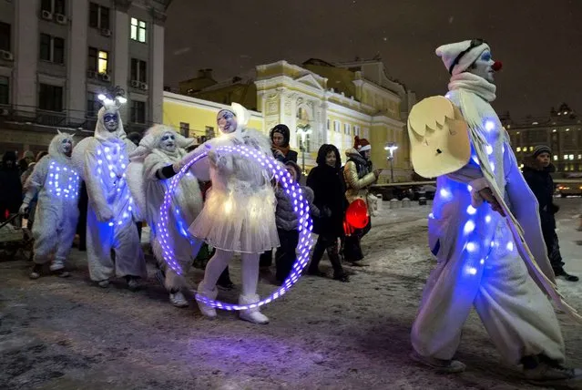 People dressed in illuminated angel costumes parade to mark Christmas Day in central Moscow, Russia, on Thursday, December 25, 2014. (Photo by Pavel Golovkin/AP Photo)