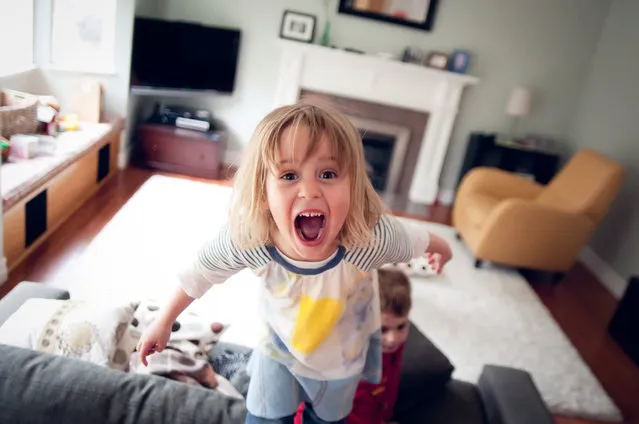 4 Year old girl standing on couch. She screaming with her mouth open. There boy and messy room behind her. (Photo by Teresa Short/Getty Images)