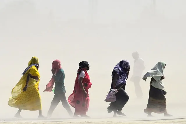 People walk through a dust storm on a hot summer day in Prayagraj on April 18, 2023. (Photo by Sanjay Kanojia/AFP Photo)