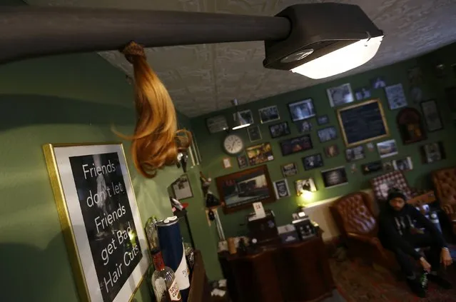 The cut off pony-tail of a customer hangs from an old street lamp illuminating Torreto barber shop in Frankfurt January 6, 2015. (Photo by Kai Pfaffenbach/Reuters)