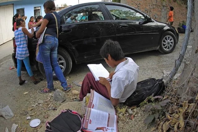 Emiliano Zapata Elementary students study on the streets in a nearby neighborhood in Chilpancingo, Guerrero, Mexico January 8, 2015. Teachers from the school, which has over 200 matriculating students, have been teaching students from various locations since December 2013 after Hurricane Manuel damaged the school building. (Photo by Jorge Dan Lopez/Reuters)