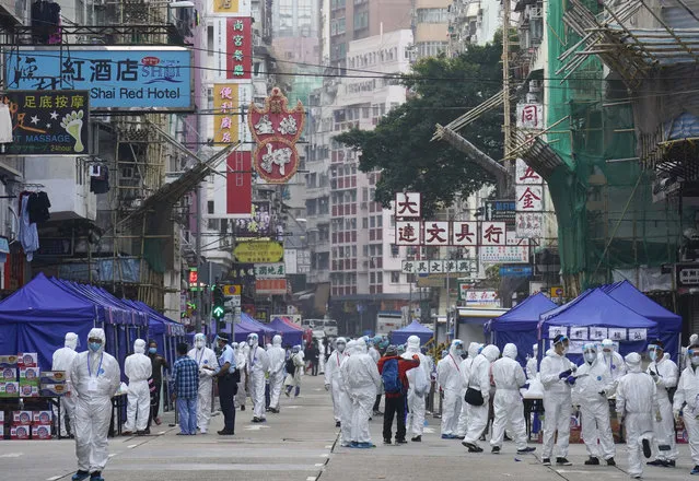 Government investigators wearing protective suits gather in the Yau Ma Tei area in Hong Kong, Saturday, January 23, 2021. Hong Kong has been grappling to contain a fresh wave of the coronavirus since November. Over 4,300 cases have been recorded in the last two months, making up nearly 40% of the city’s total. (Photo by Vincent Yu/AP Photo)