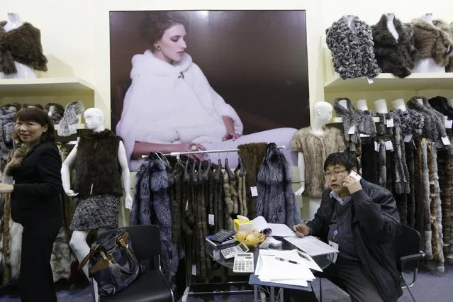 An exhibitor speaks on a mobile phone at his booth next to fur clothing at the 2015 China Fur and Leather Products Fair in Beijing, January 15, 2015. (Photo by Jason Lee/Reuters)