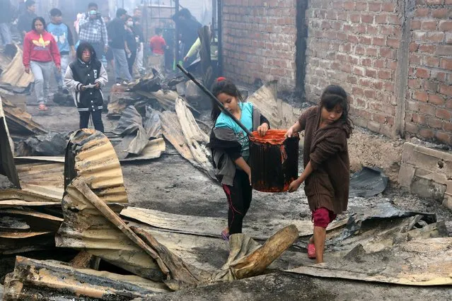 Girls carry a bucket of water at a scene of a fire at 'Cantagallo' shanty town in Rimac district of Lima, Peru November 4, 2016. (Photo by Guadalupe Pardo/Reuters)