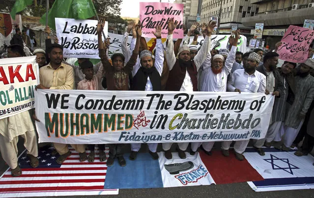 Supporters of a Pakistani religious group 'Fidaiyan-e-Khetm-e-Nebuwwat' stand on the representations of American, French and Israeli flags and chant slogans during a demonstration to protest against caricatures published in French magazine Charlie Hebdo, in Karachi, Pakistan, Saturday, January 17, 2015. (Photo by Fareed Khan/AP Photo)