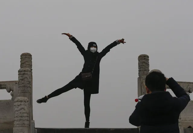 A woman wearing a protective mask against smog poses for photos at the Temple of Heaven Park in Beijing, China, 08 December 2015. City schools closed on 08 December as Beijing issued its first-ever smog red alert, advising residents to stay indoors and children not to go to school until 10 December lunchtime. The new alert issued by the city's emergency management headquarters represented the highest-level warning issued for the first time since a four-colour scale was introduced in 2013. (Photo by Rolex Dela Pena/EPA)