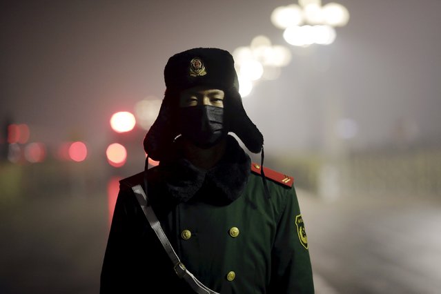 A paramilitary policeman wears a mask on a cold morning as people gather for a flag-raising ceremony amid heavy smog at the Tiananmen Square, after the city issued its first ever "red alert" for air pollution, in Beijing December 9, 2015. (Photo by Damir Sagolj/Reuters)