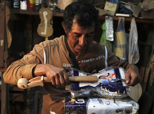 Trash recycler and craftsman Nicolas Gomez makes a violin from a paint tin and dinner fork for the Orchestra of Recycled Instruments of Cateura, in Cateura, near Asuncion, May 22, 2013. (Photo by Jorge Adorno/Reuters)