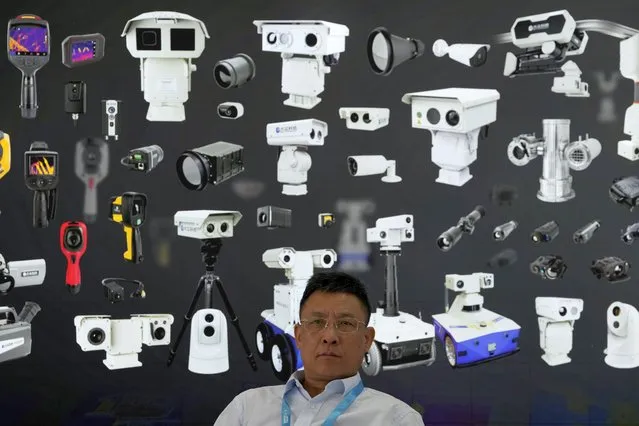 A vendor sits near a board depicting surveillance cameras during Security China 2023 in Beijing, on June 9, 2023. After years of breakneck growth, China's security and surveillance industry is now focused on shoring up its vulnerabilities to the United States and other outside actors, worried about risks posed by hackers, advances in artificial intelligence and pressure from rival governments. The renewed emphasis on self-reliance, combating fraud and hardening systems against hacking was on display at the recent Security China exhibition in Beijing. (Photo by Ng Han Guan/AP Photo)