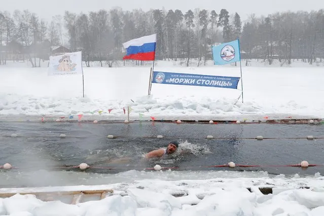 A participant swims during the winter Cryathlon tournament which includes running on snow, ski racing and ice swimming, in the settlement of Malakhovka in Moscow Region, Russia on March 7, 2021. (Photo by Evgenia Novozhenina/Reuters)
