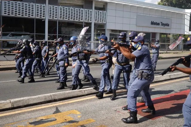 Members of the South African Police Service (SAPS) fire rubber bullets at students during a protest in Braamfontein, Johannesburg, on March 10, 2021. A passerby was shot dead on March 10, 2021 after South African police moved to disperse students protesting against refusal by a top  Johannesburg-based university to register those in arrears with tuition fees, local media and the university said. Clashes erupted when police used rubber bullets to break up a group of students who were blocking roads with rubble and disrupting traffic in downtown Johannesburg around  the Wits campus precinct. (Photo by Michele Spatari/AFP Photo)